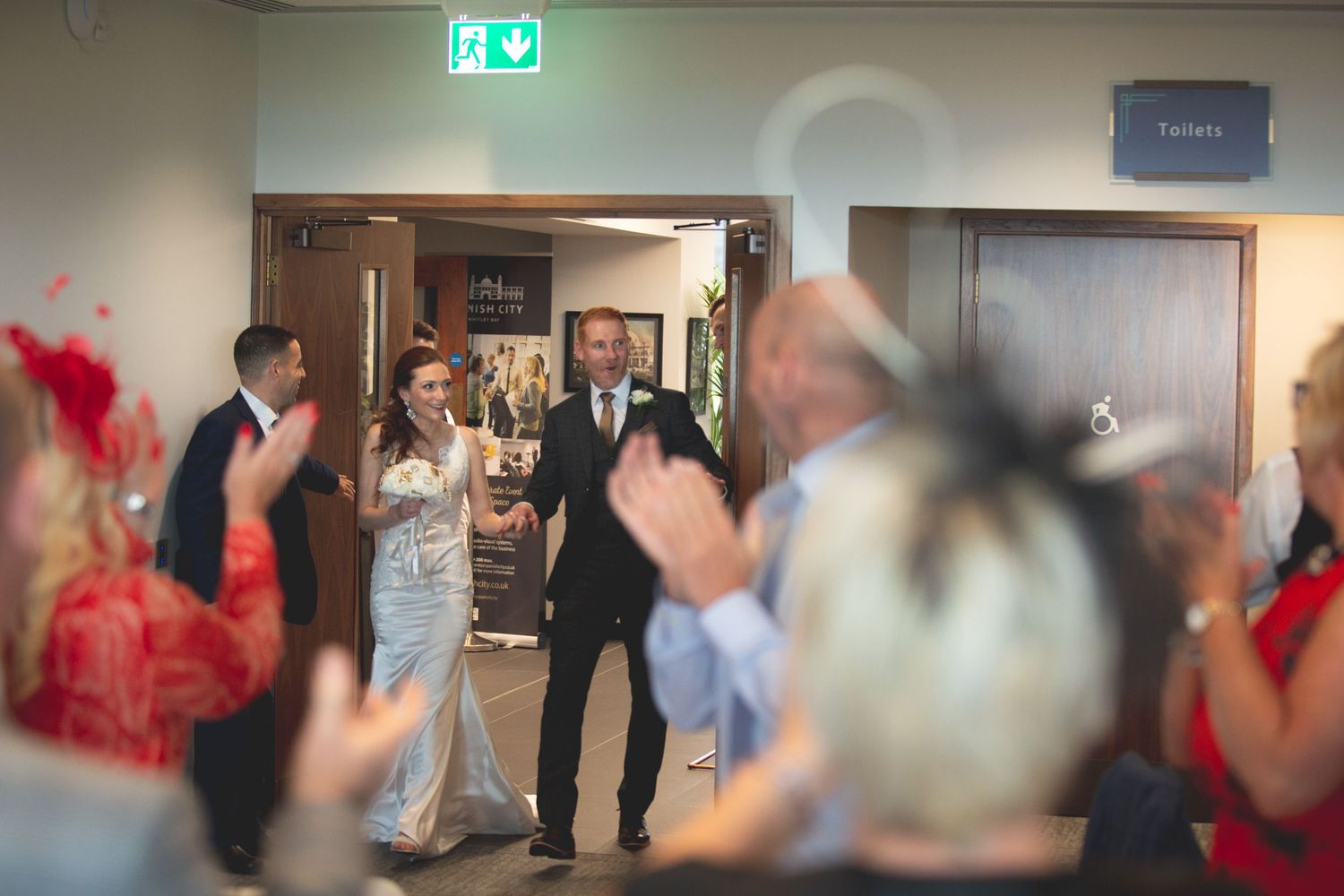 Blurred motion of wedding guests entering reception area with festive decorations.