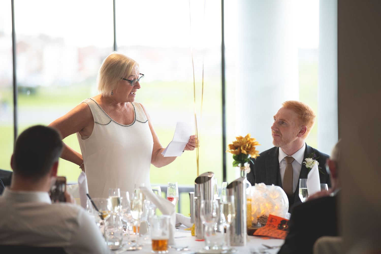 Wedding reception scene with sunflowers and glassware on dining table.