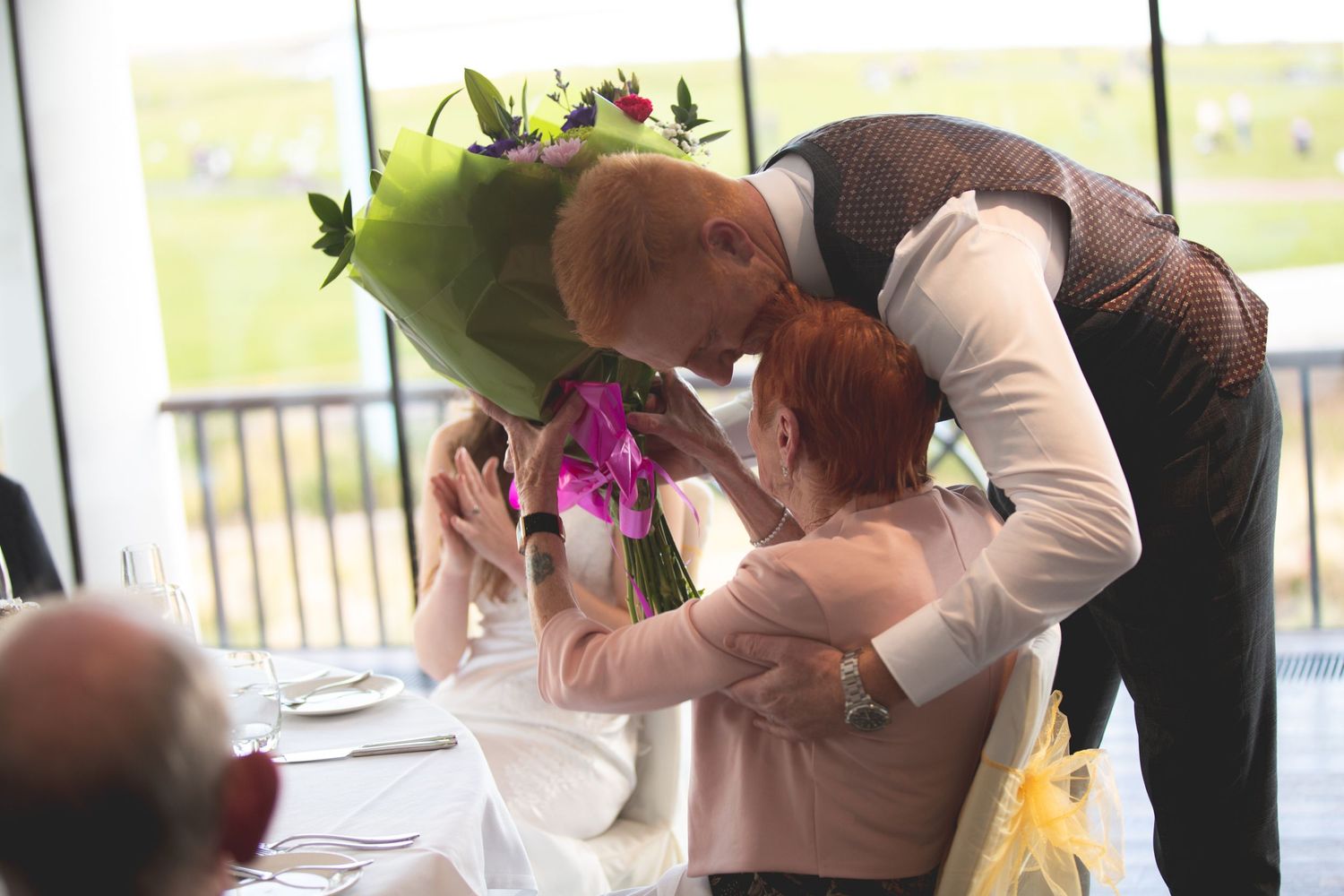 Guests embrace during an emotional moment at a wedding reception.