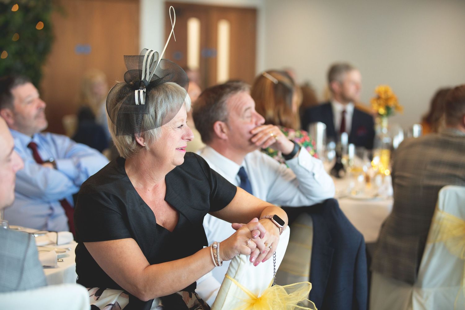 Wedding guests enjoy entertainment and speeches during an indoor reception.