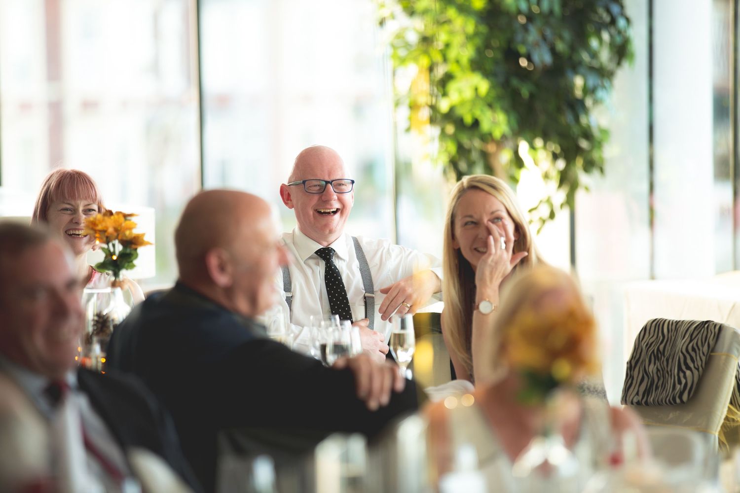 Wedding guests engage in lively conversation during a sunlit reception.