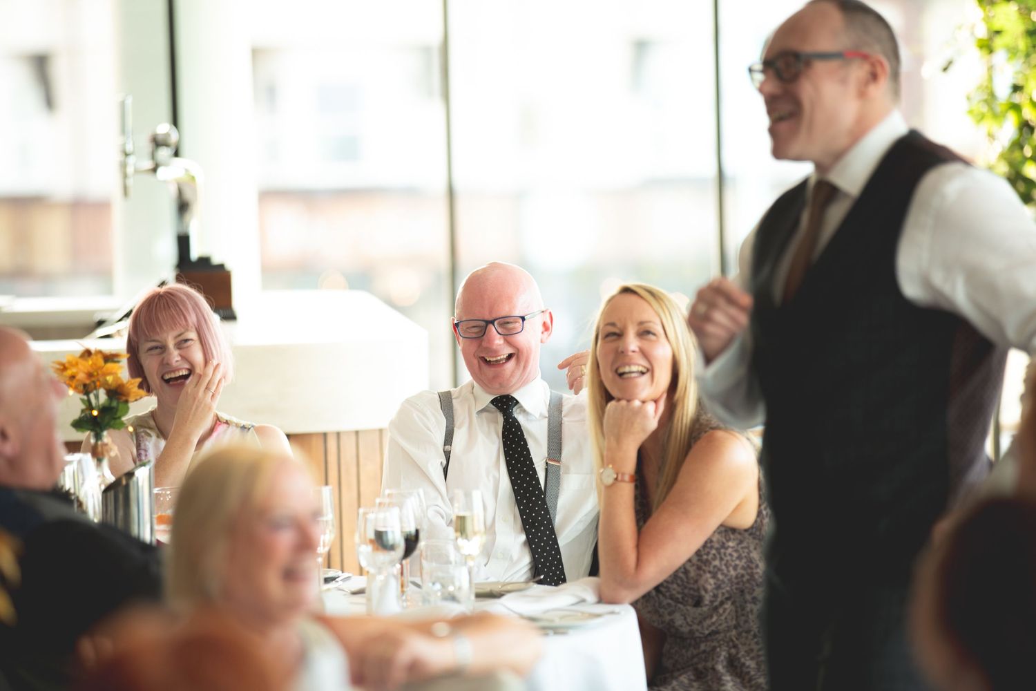 Guests enjoying a lively conversation during a formal dinner service with a server attending.