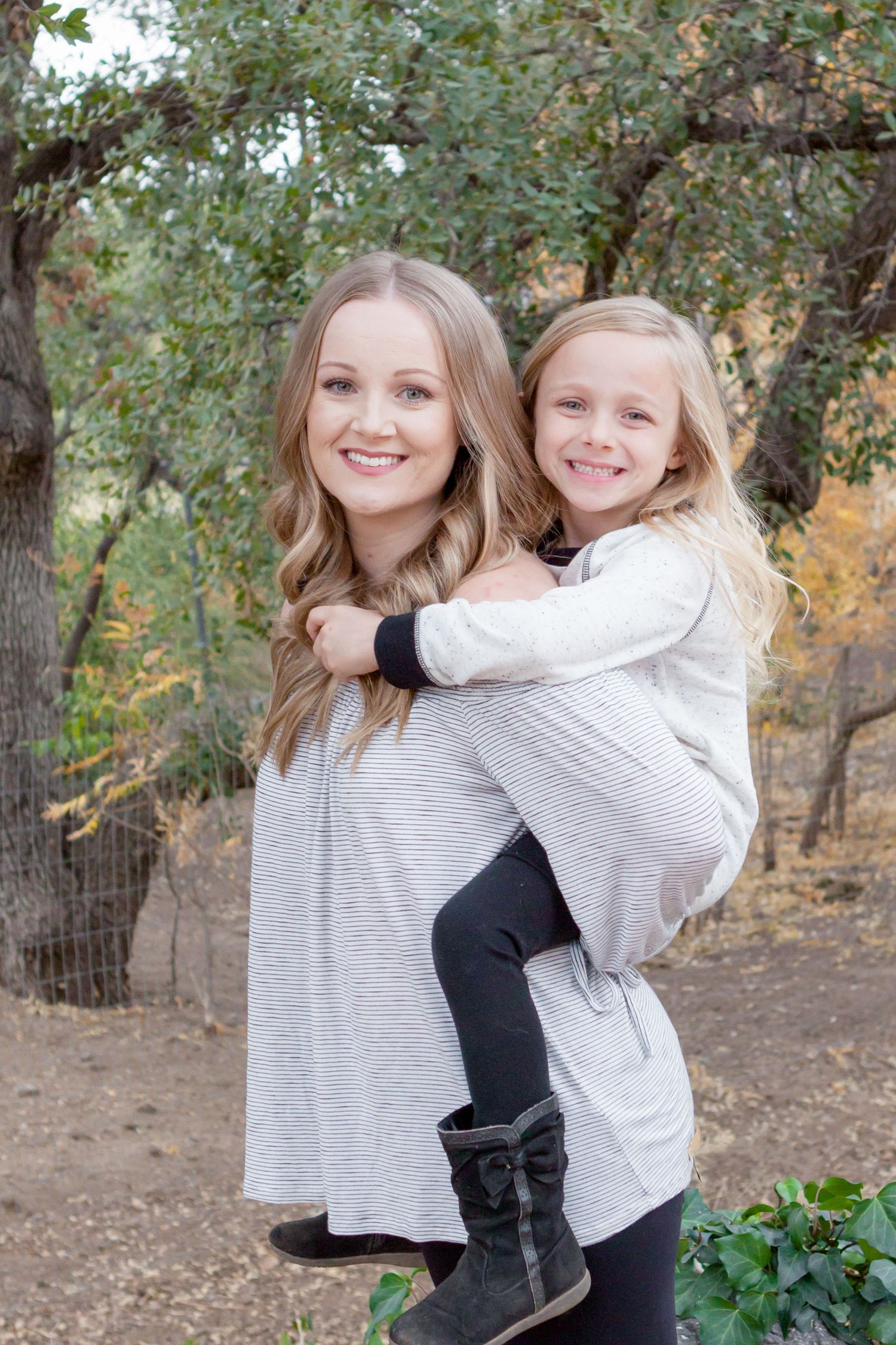 A portrait of a mom with her young daughter on her back