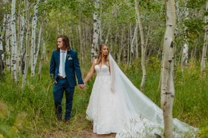 A wedding couple walking through a scenic aspen grove with flowing white dress.