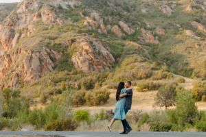 Dancing couple silhouetted against rocky mountain landscape during golden hour.