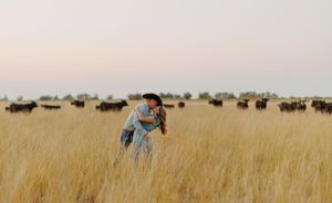 A romantic lift in a golden savanna field with wildebeest grazing in the background.
