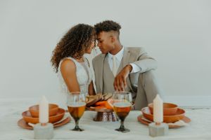 Romantic dinner setting with candles and orange place settings for two.