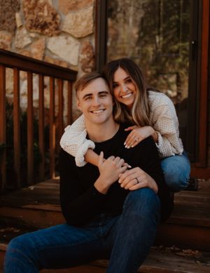A casual couple shares a tender moment on wooden porch steps.