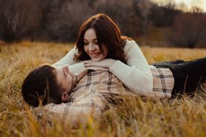 Intimate couple lying in golden autumn grass during sunset portrait session.