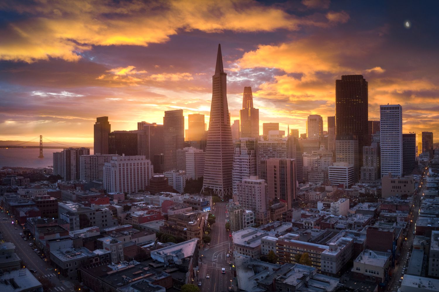 San Francisco skyline at sunset with dramatic orange clouds and the Transamerica Pyramid silhouetted against the sky.