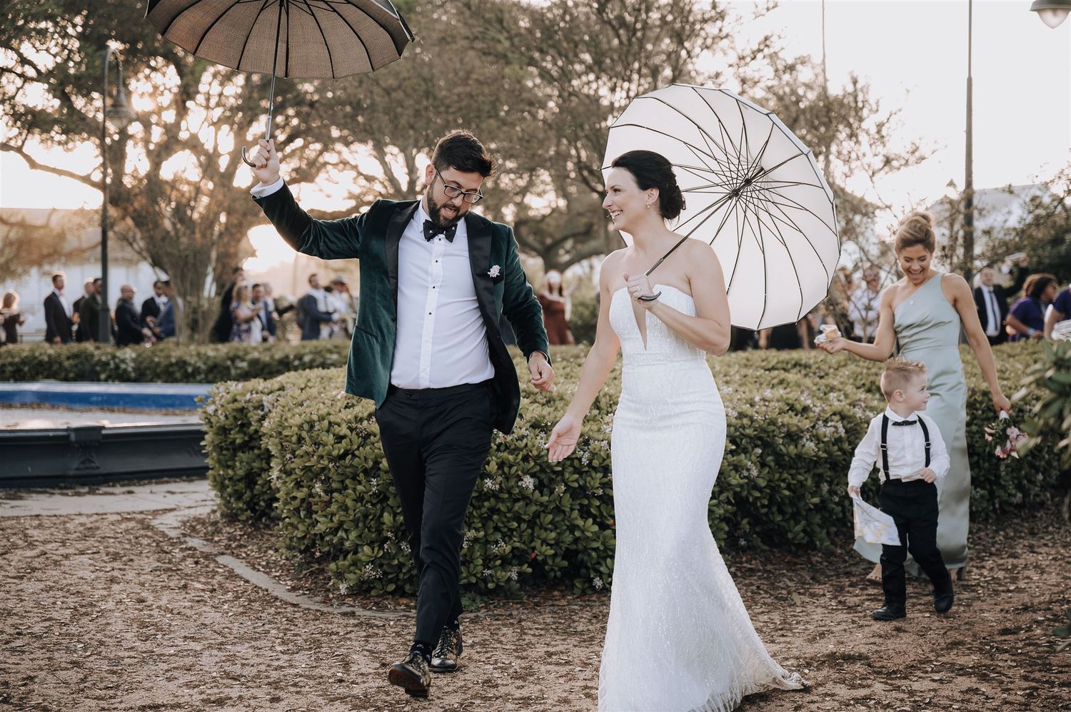 A couple walks joyfully with white parasols during their wedding celebration.