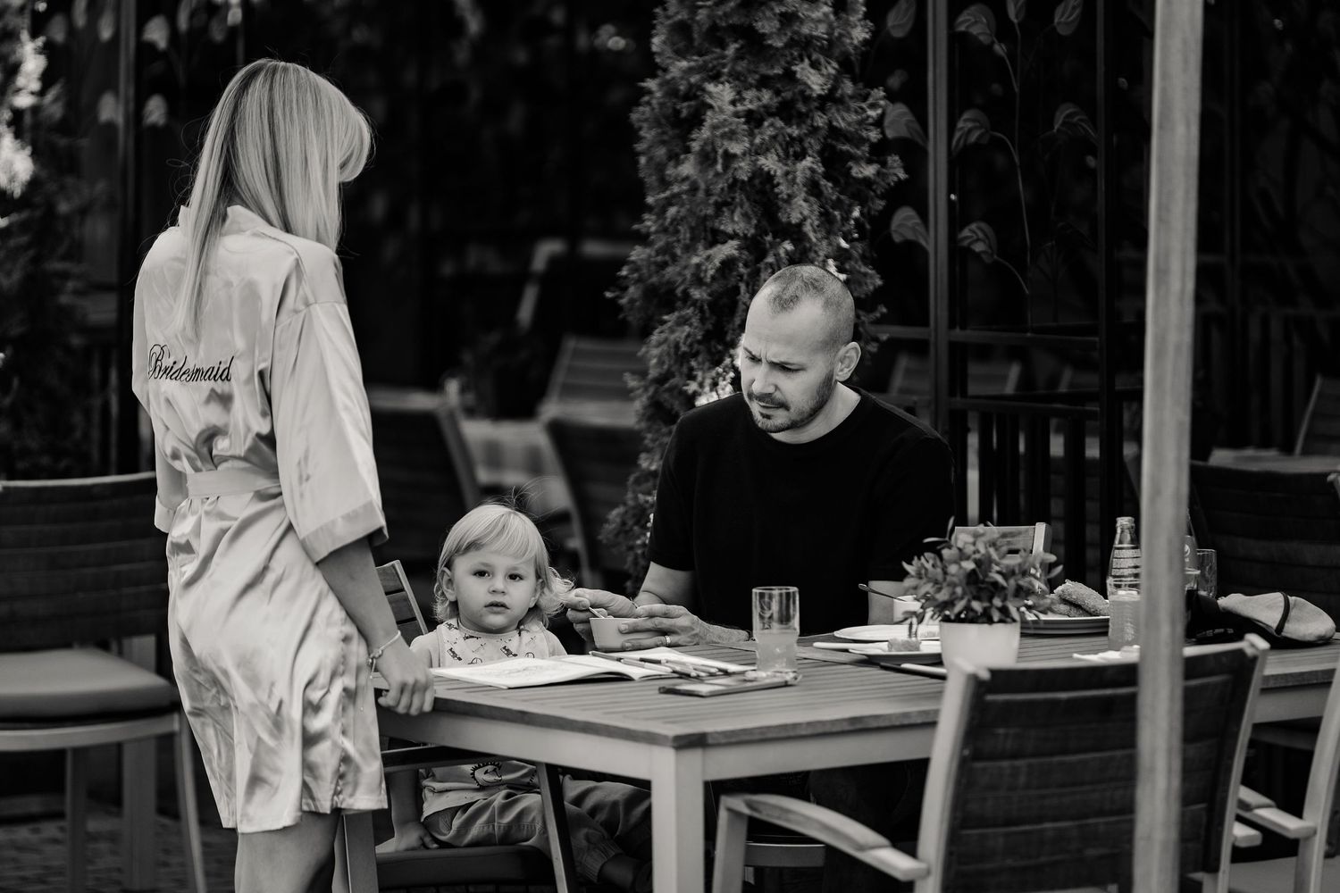 Black and white photo of outdoor dining scene with people at a patio table.