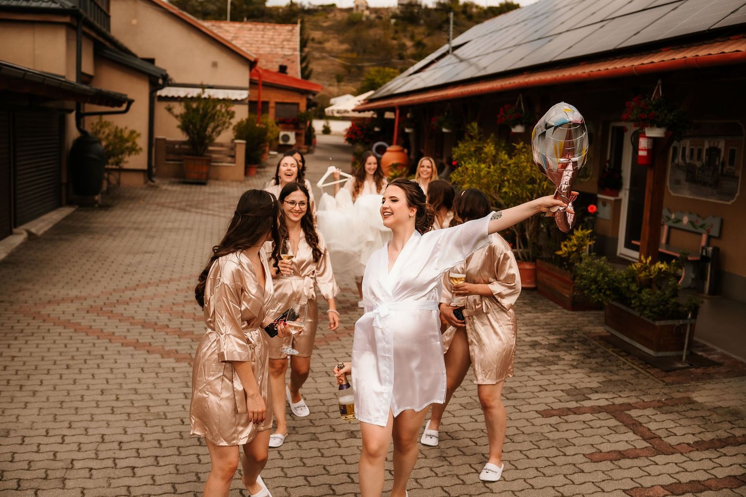 Group in matching silk robes walking and celebrating on a cobblestone street.