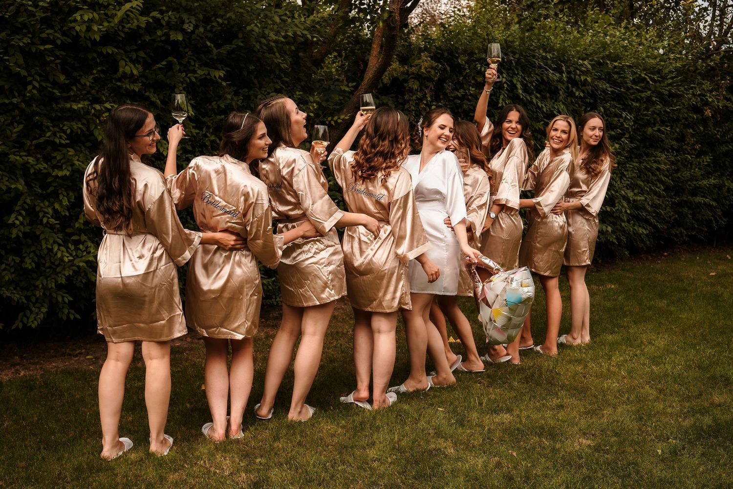 Festive group photo with people in matching silk robes posing on grass.
