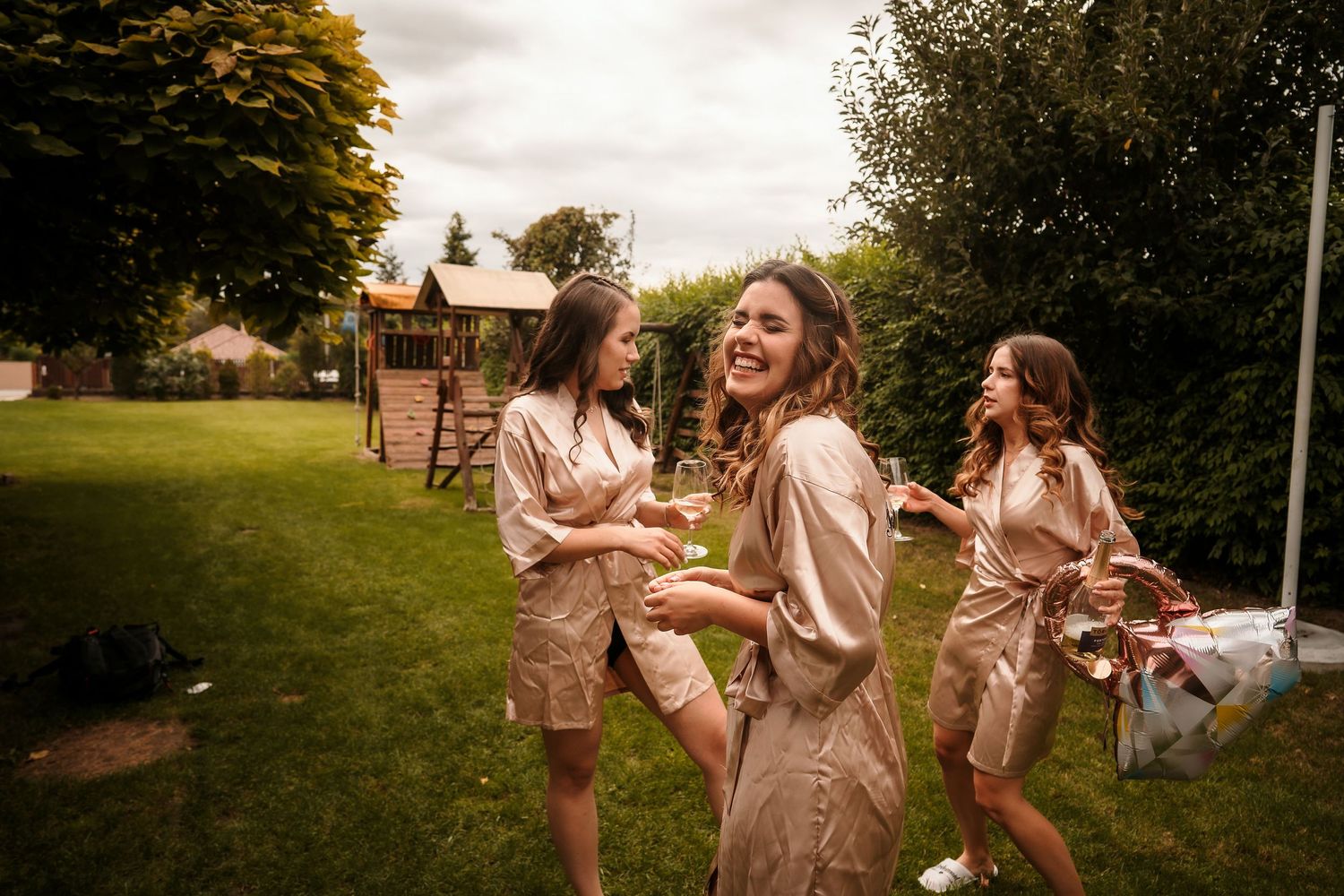 Group wearing matching beige outfits dancing and celebrating outdoors on a grassy lawn.