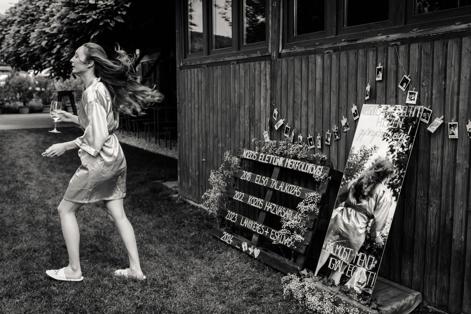 Black and white photo of someone running past wooden building with decorative signs.