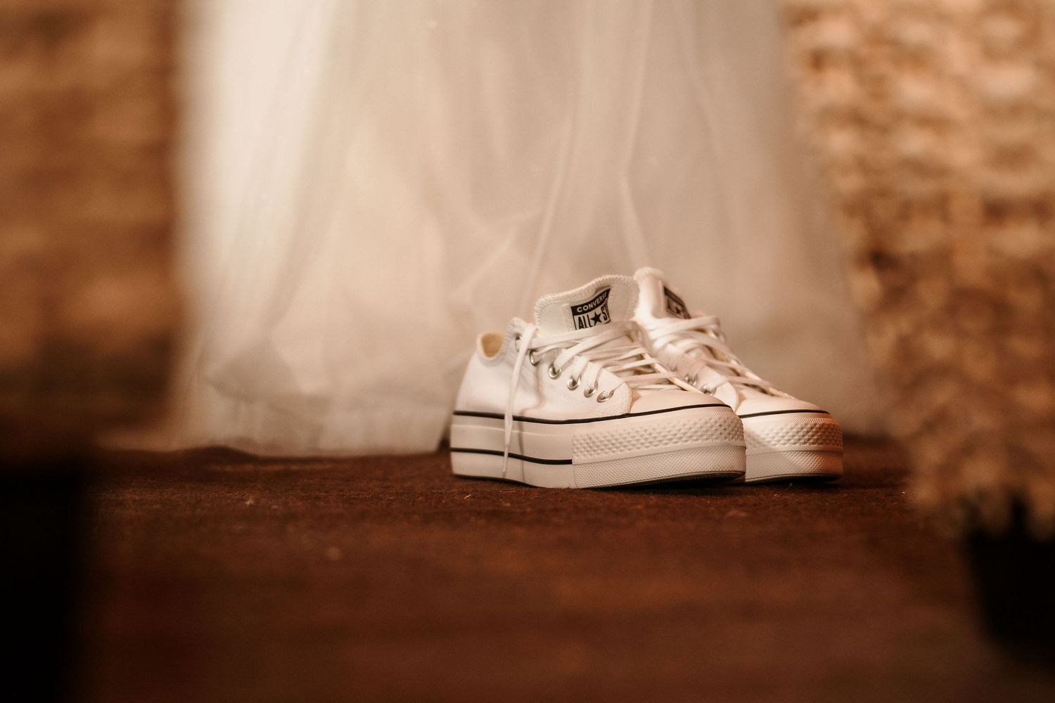 White wedding sneakers displayed against rustic background with soft focus.