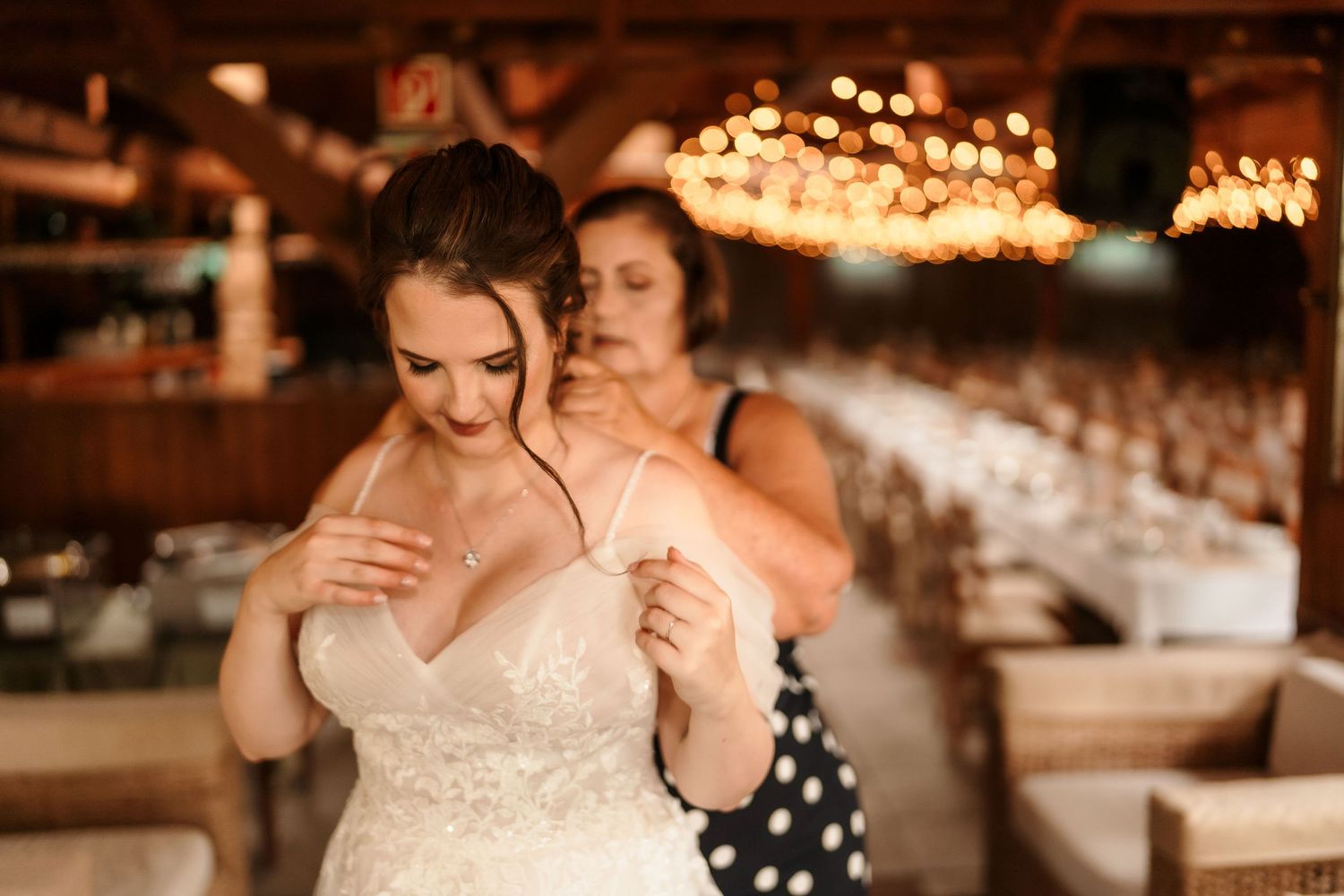 An intimate dance moment captured at a wedding reception under warm string lights.