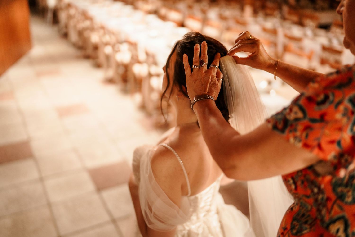 Final wedding preparations with delicate attention to bridal details in warm lighting.