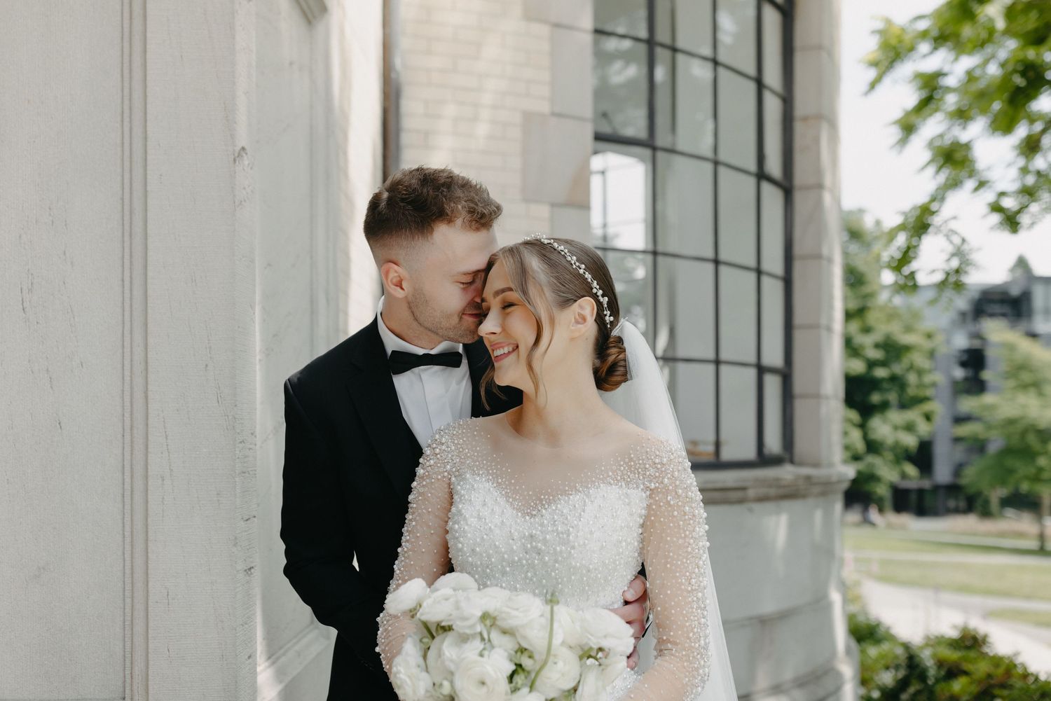 A tender moment captured between newlyweds against a classic architectural backdrop.