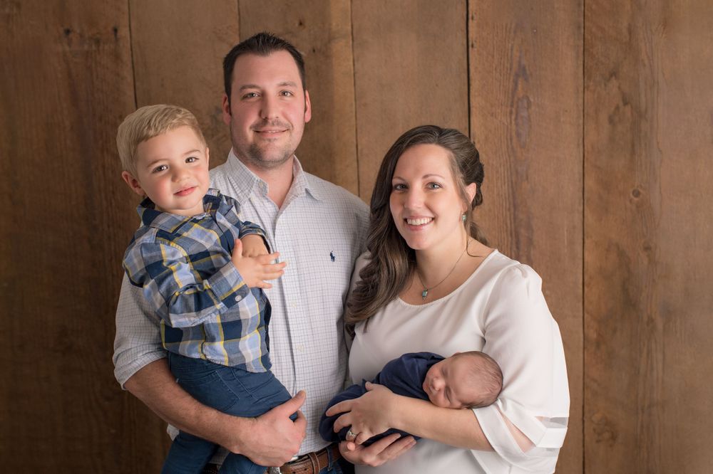 A warm family portrait against wooden paneling in soft natural light.
