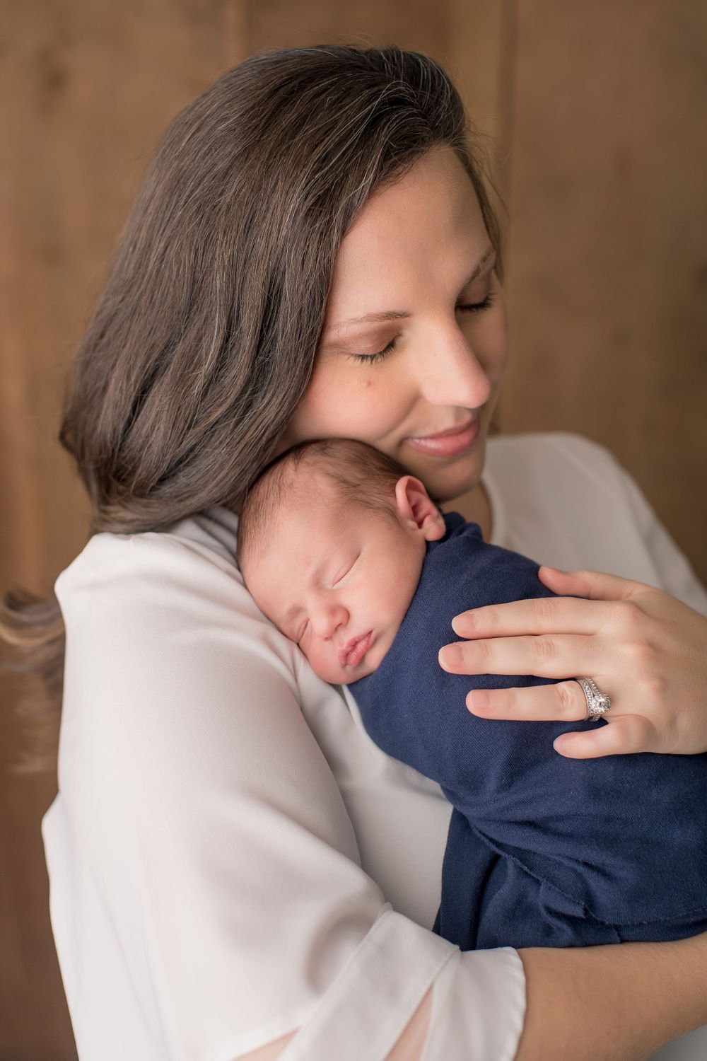 A gentle embrace captured in soft lighting against rustic wooden backdrop.