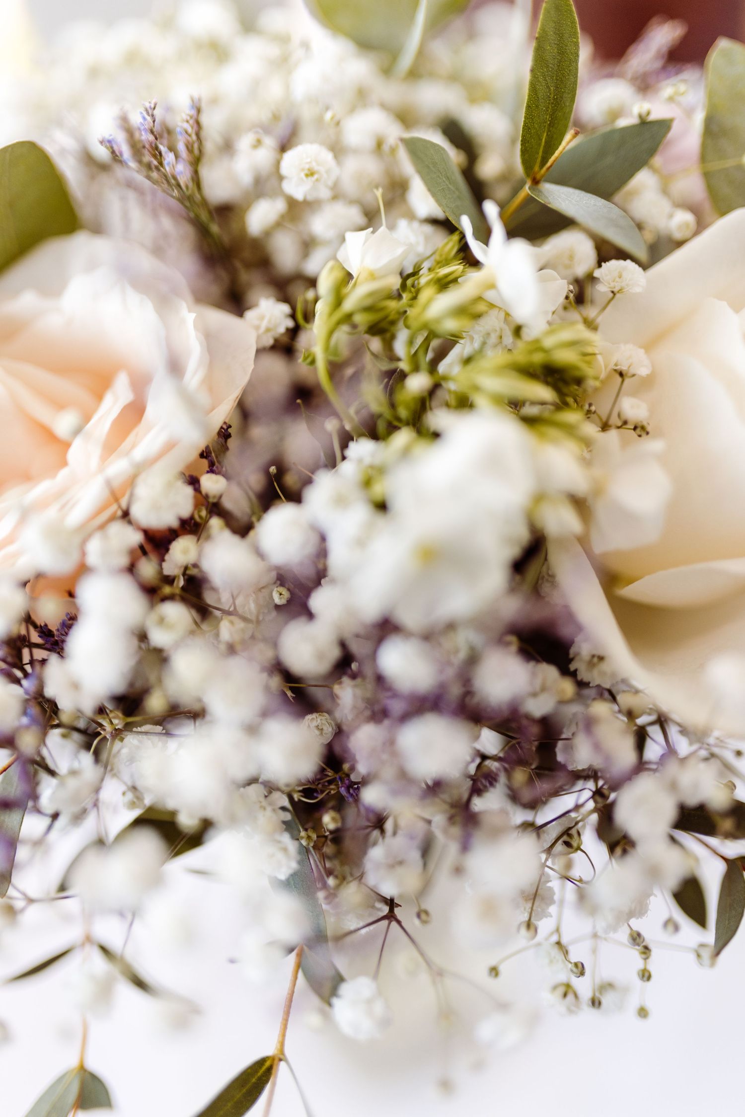 Delicate floral arrangement with roses, baby's breath and greenery in soft focus.