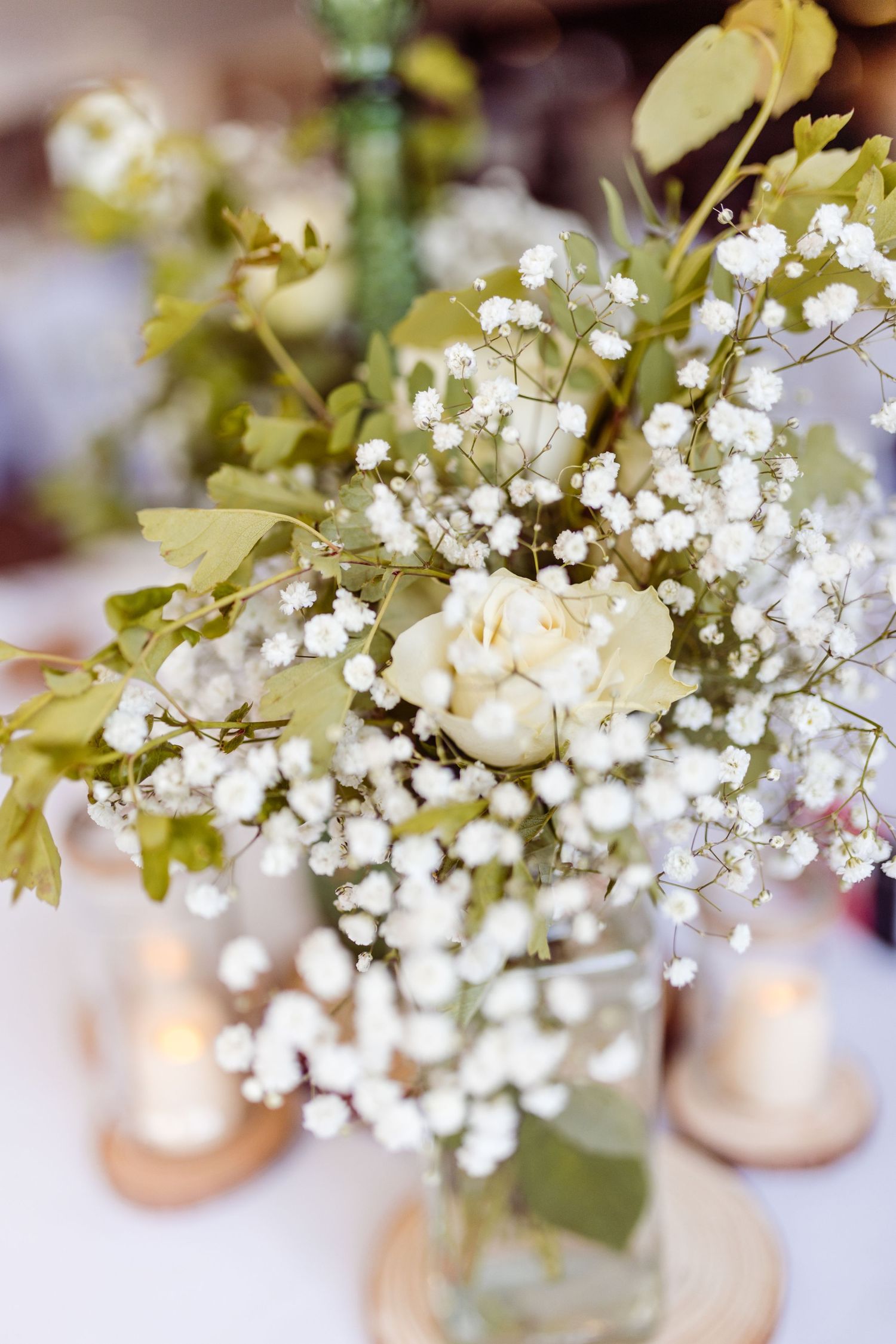 White baby's breath and roses arranged in glass vase for wedding centerpiece.