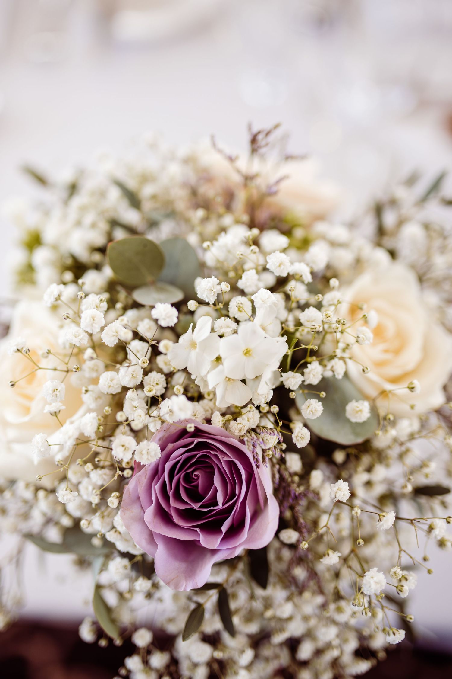 Delicate wedding bouquet featuring purple and cream roses with baby's breath flowers.