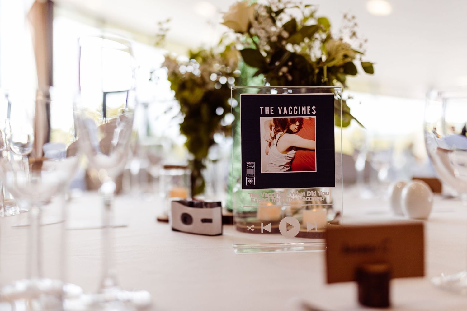 Wedding reception table setting with decorative floral centerpiece and book-themed table number display.