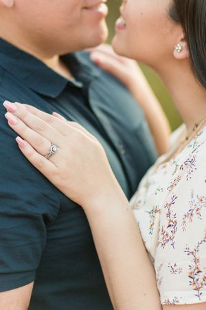 Close-up of hands showing an engagement ring against floral clothing.