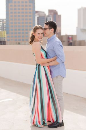 Couple dancing together on urban rooftop, with woman wearing colorful striped maxi dress.