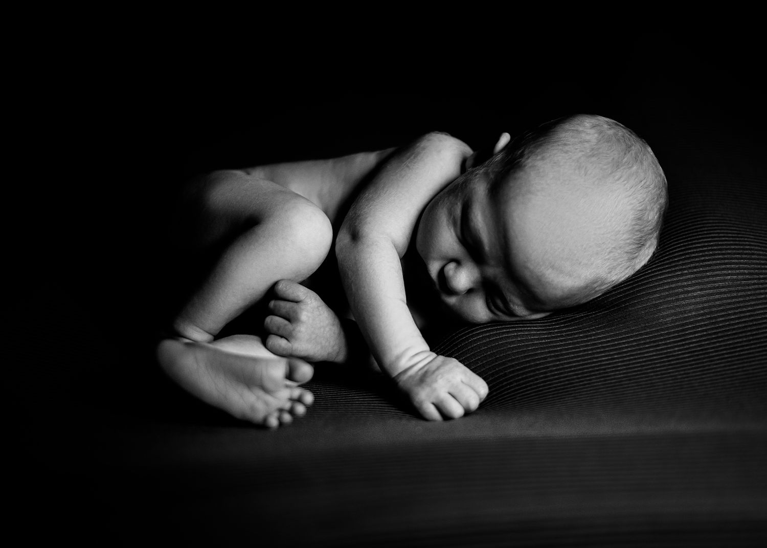 Black and white photo of a newborn boy, capturing a peaceful and tender moment.