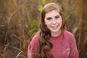 Senior graduate posing in wheat field.
