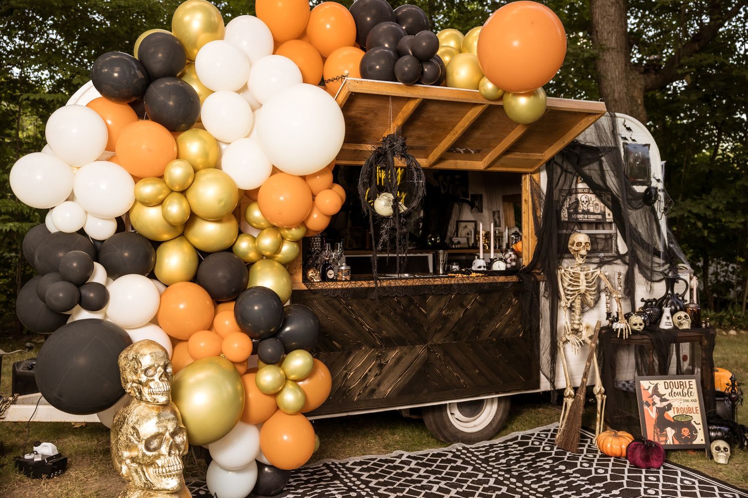 Halloween-themed food truck decorated with orange, black, and gold balloons and spooky decor.
