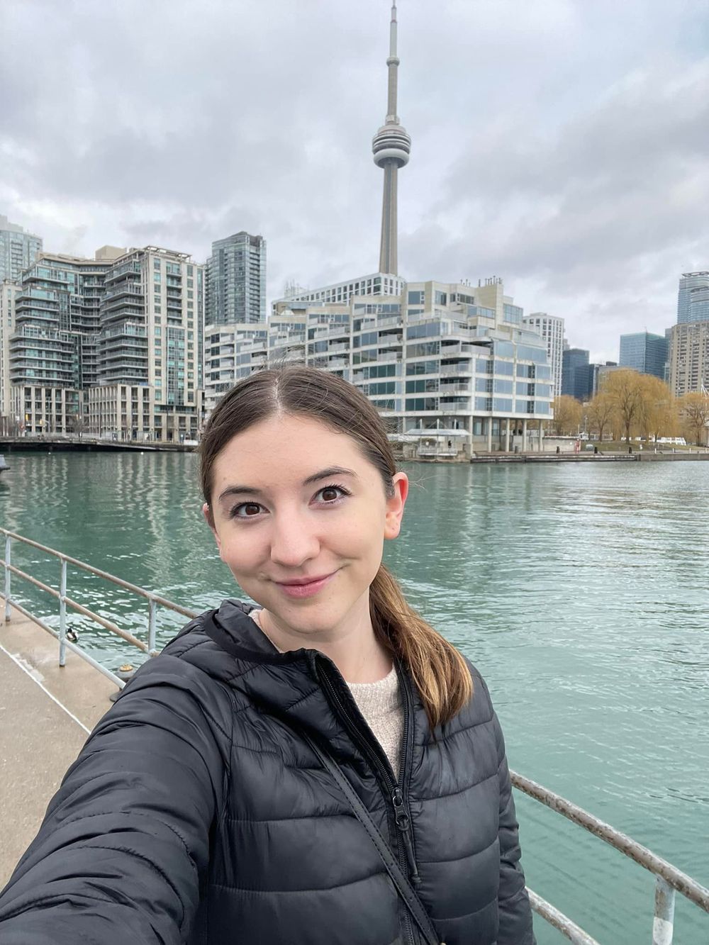 Girl taking a selfie on the harbour front with CN Tower in the background.