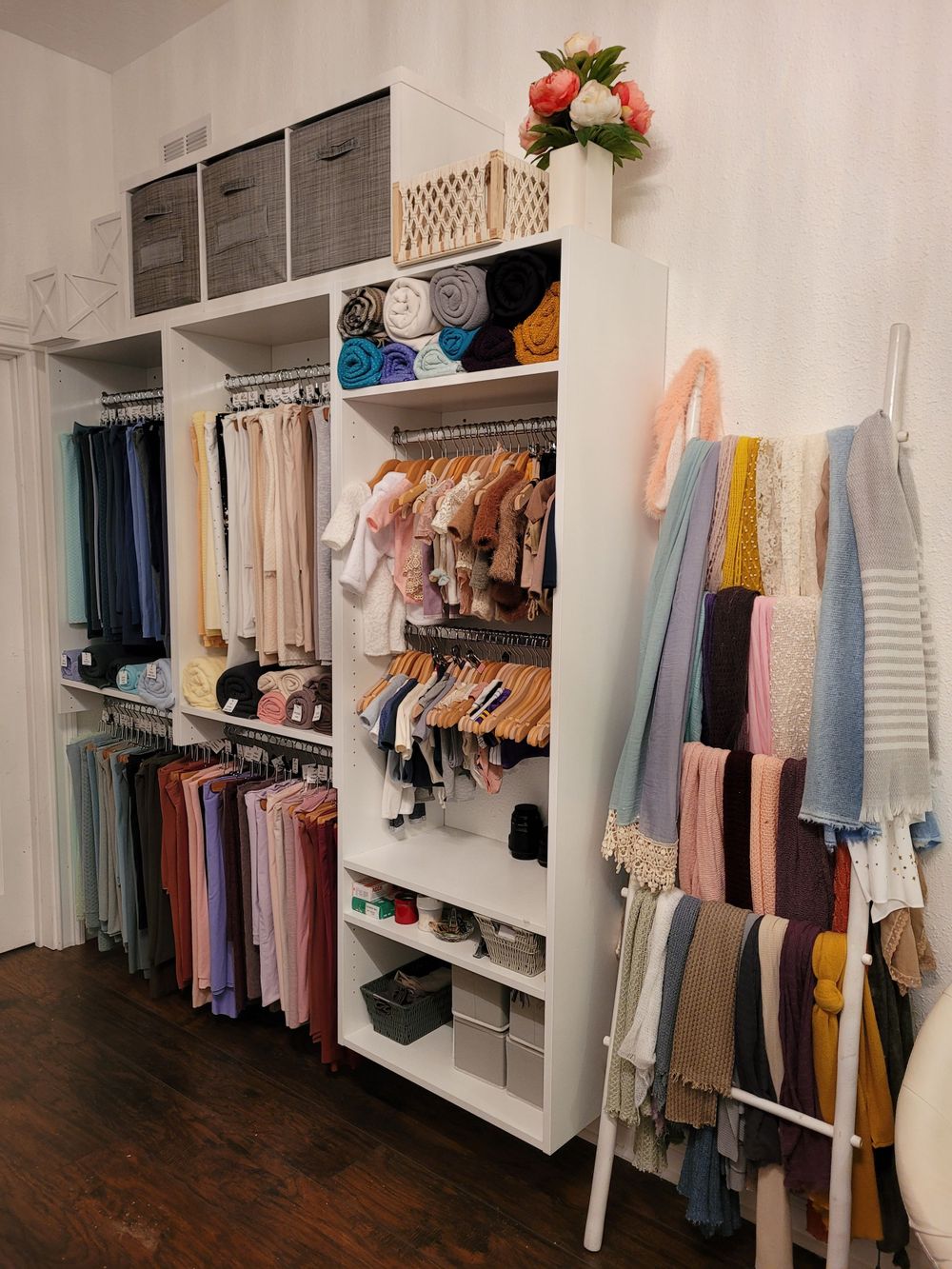 Organized closet system with white shelving displaying colorful clothing and accessories.
