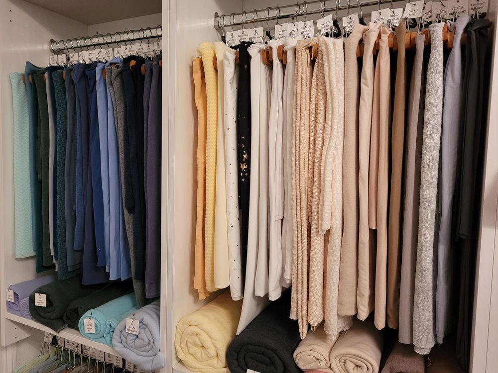 Organized closet rack featuring garments in neutral colors from dark to light.