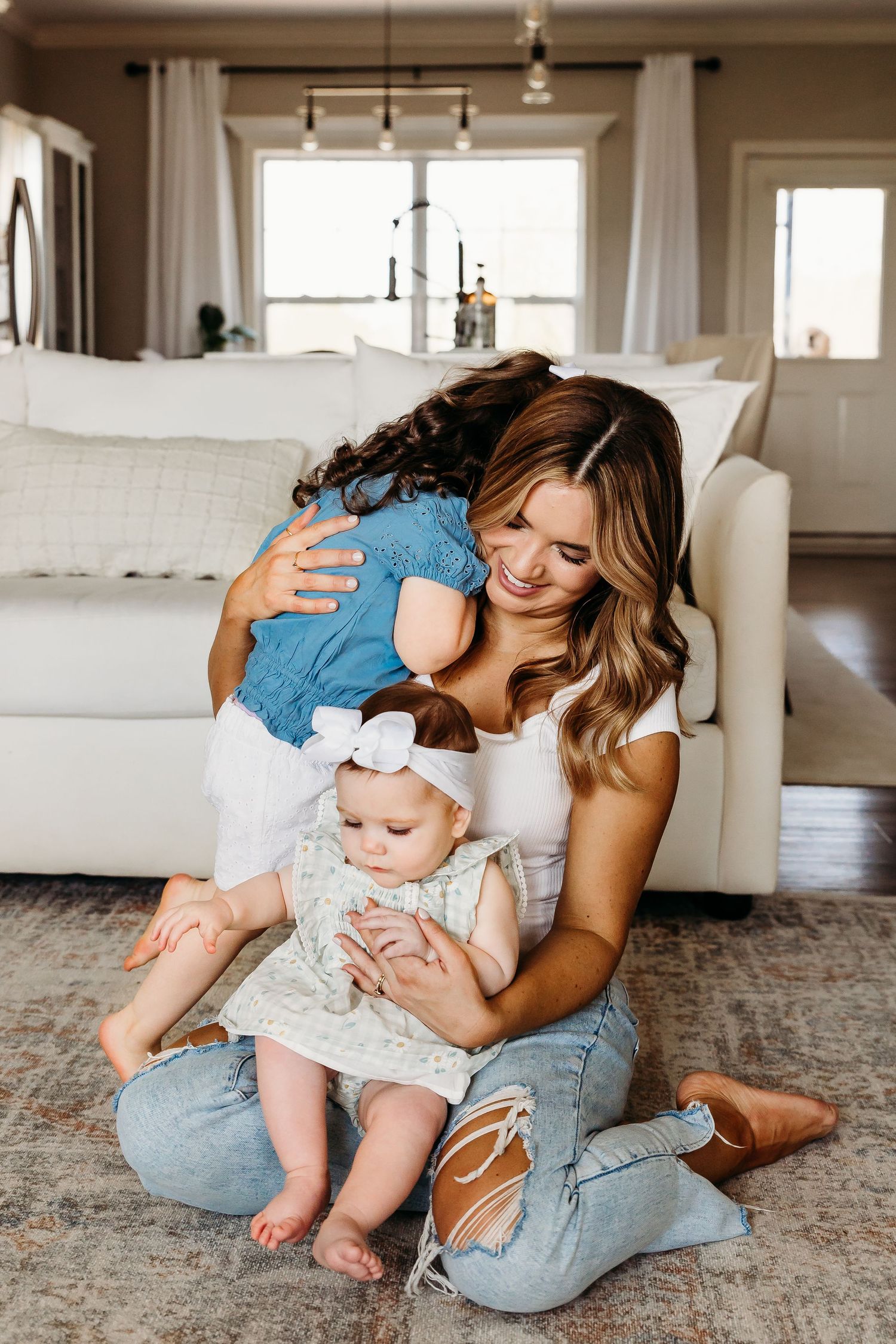 Candid family moment on living room floor with white couch in background.