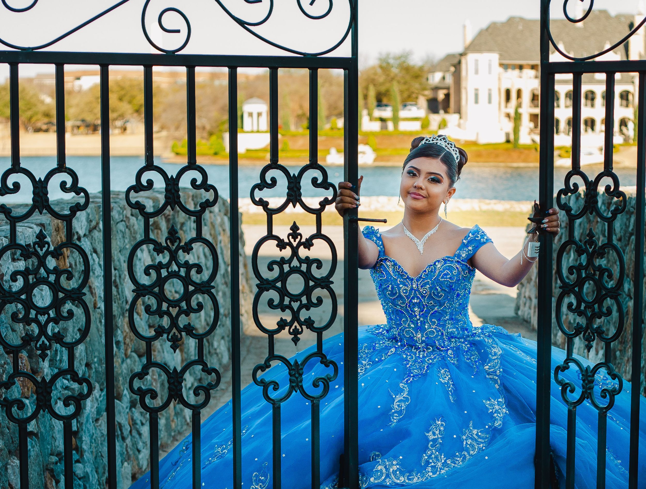 A sparkling blue ballgown photographed through ornate wrought iron gates.
