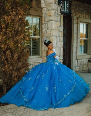 Stunning blue quinceañera ball gown with sparkly details photographed at stone building.