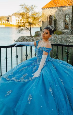 Blue princess ball gown with crystal embellishments photographed by waterfront railing.
