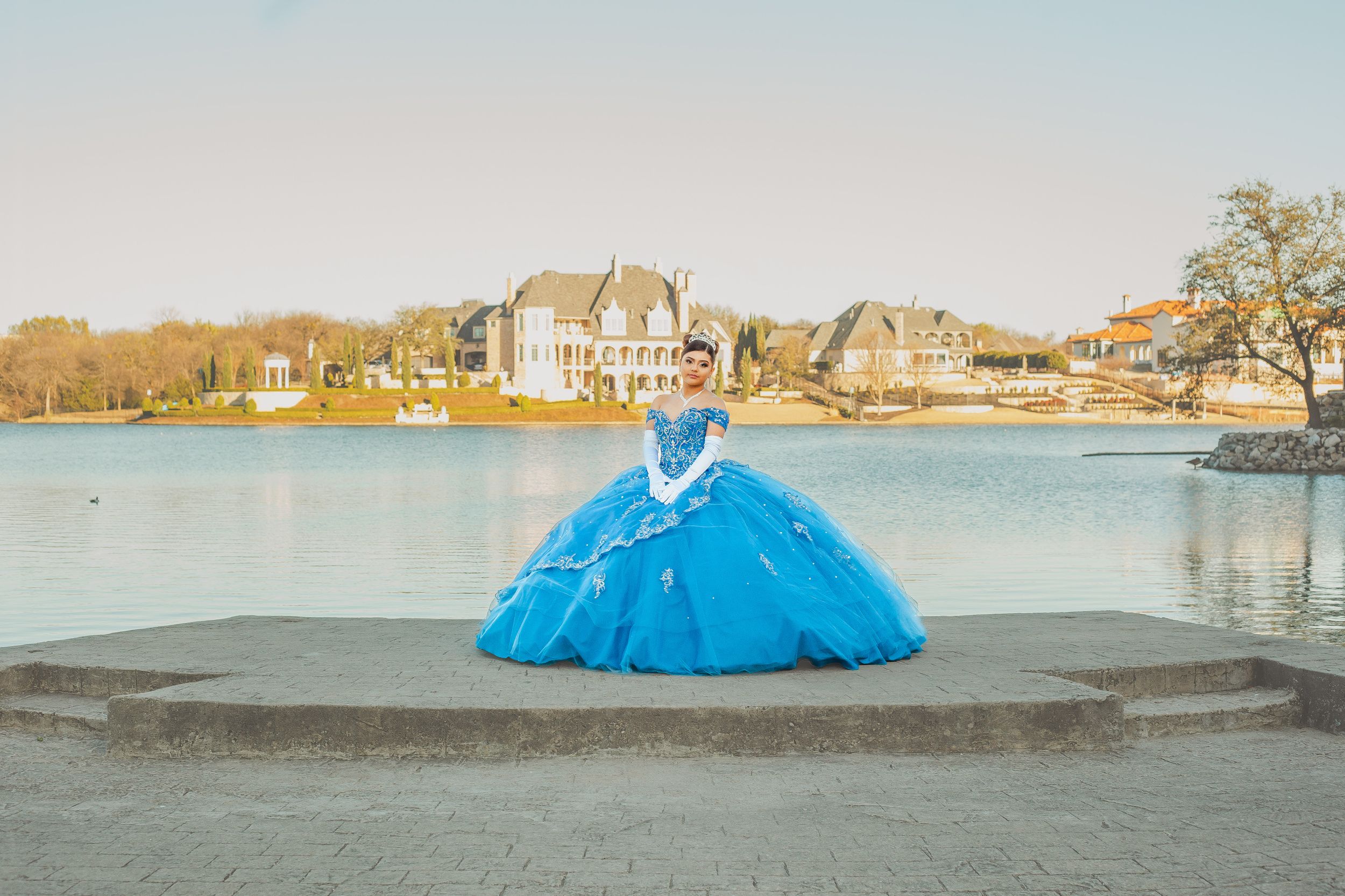 A bright blue formal gown photographed against a waterfront backdrop.