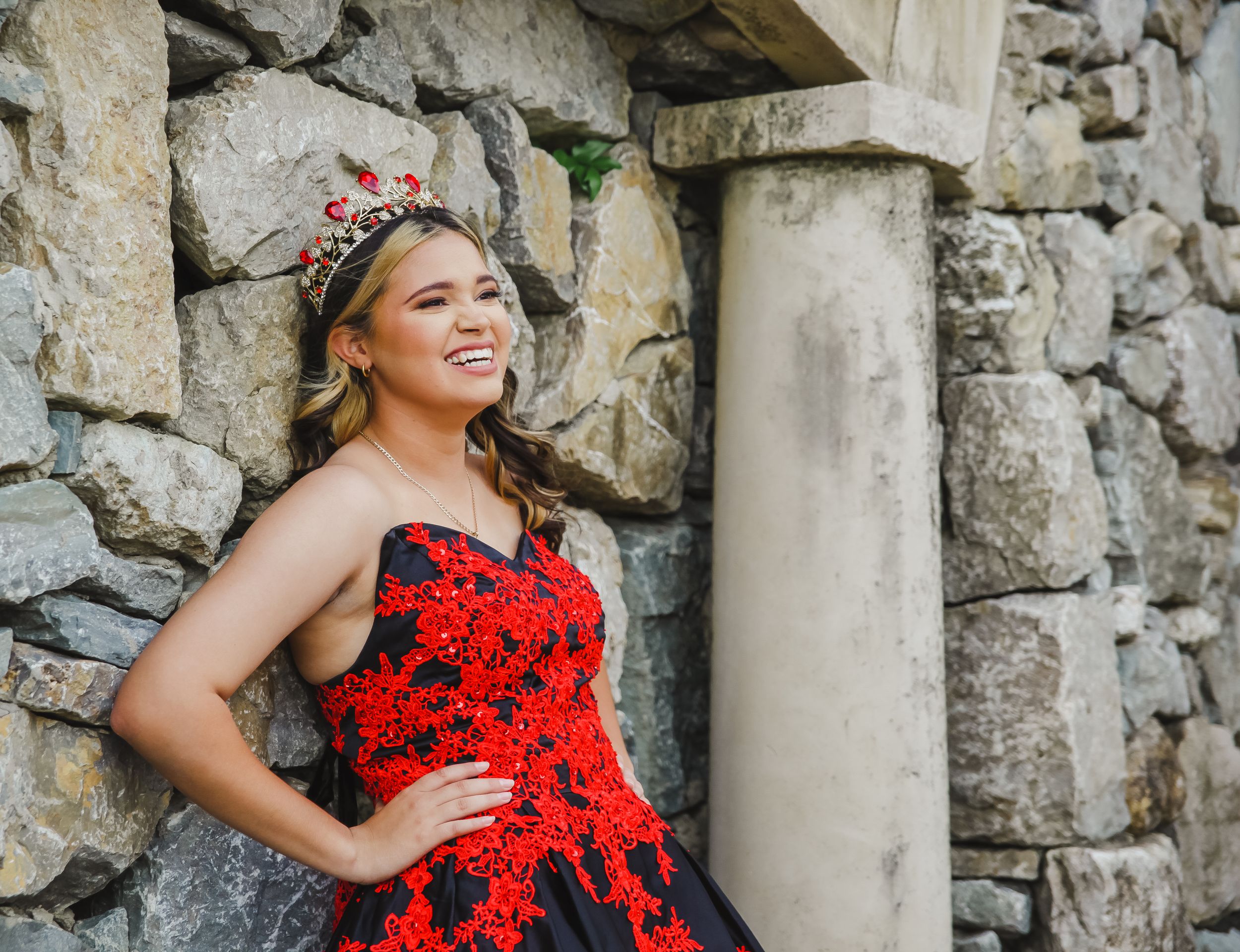 Red lace formal dress photographed in stone archway setting.
