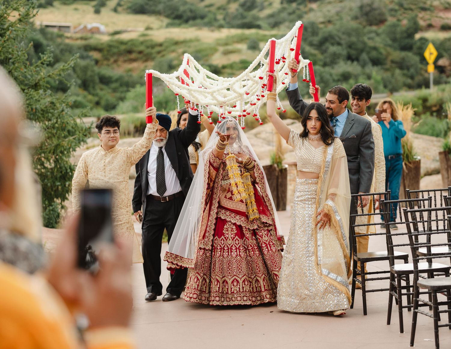 Outdoor wedding ceremony setup with red and gold traditional Indian decorations.