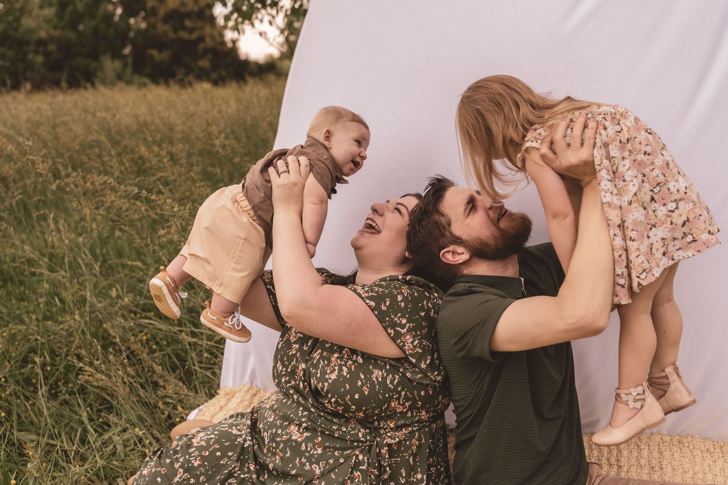 A family of four playing and snuggling on a woven blanket for their family photography session
