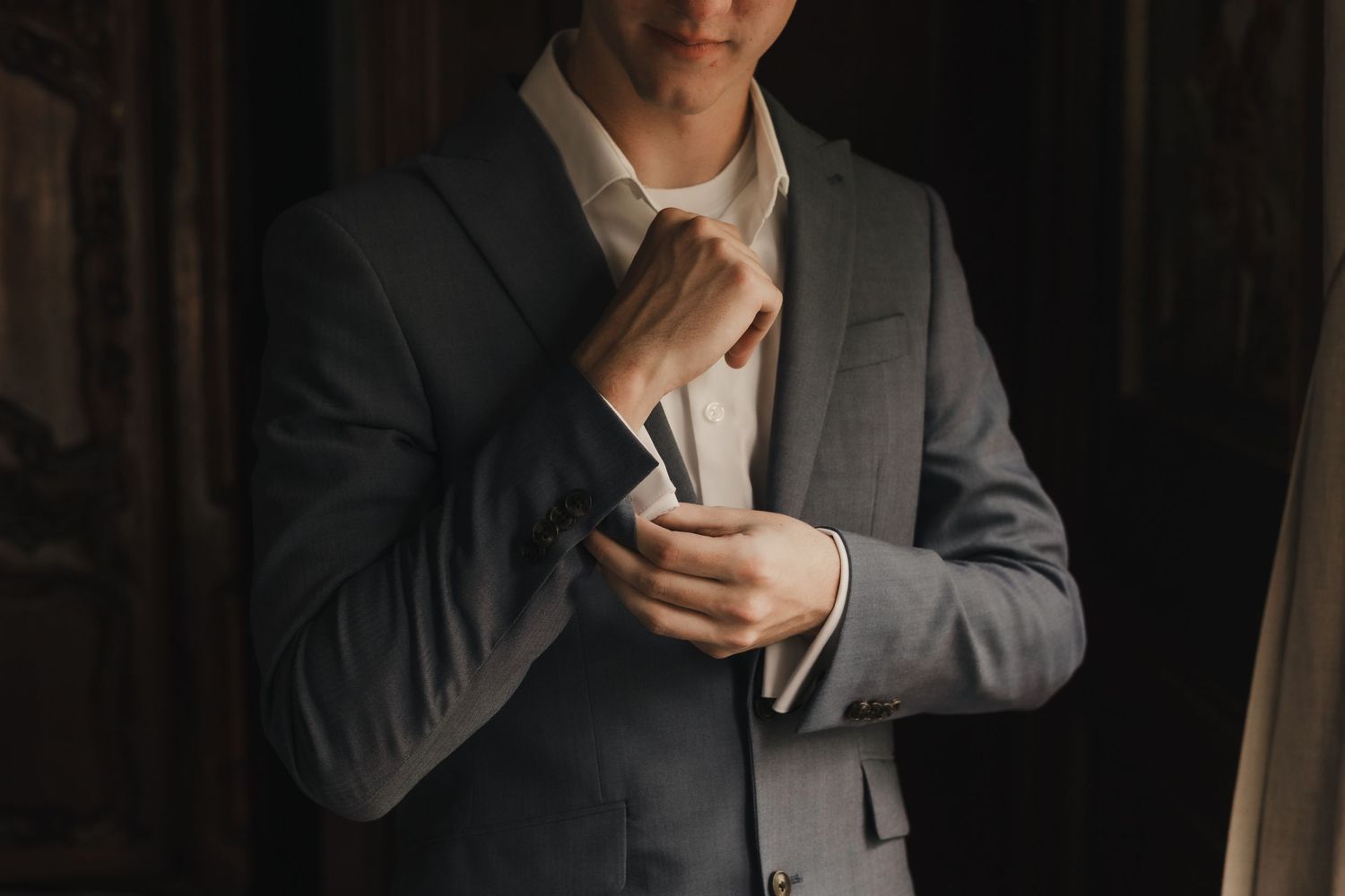 A groom buttoning his sleeves while getting dressed before his wedding ceremony