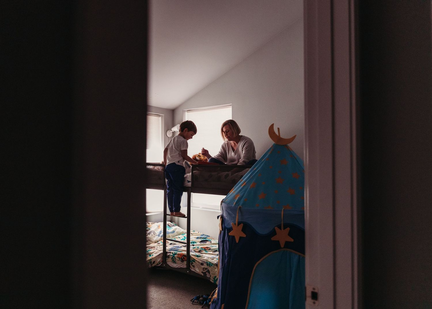 Intimate family moment viewed through doorway with soft lighting.