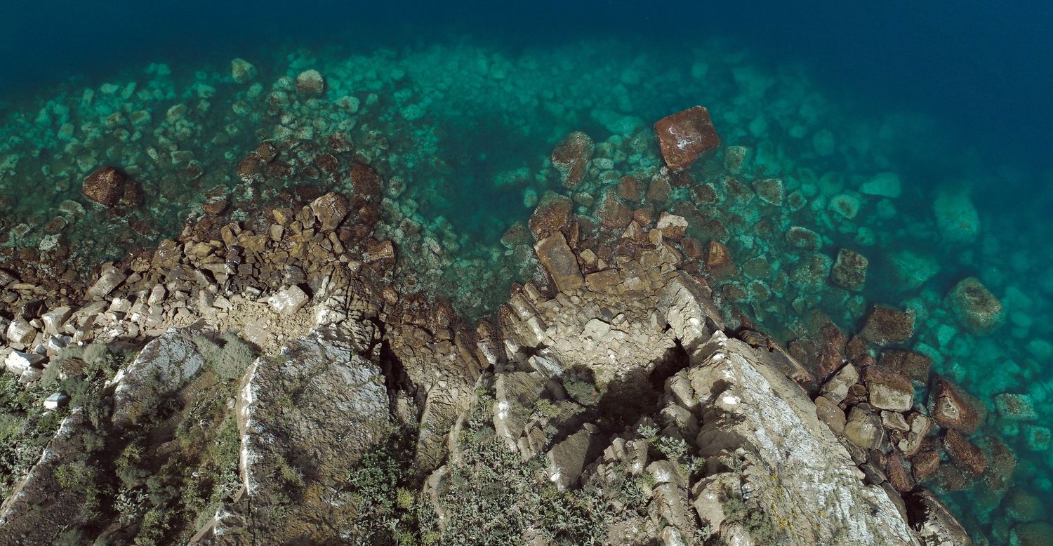 Aerial view of coral reefs and rock formations in crystal clear turquoise ocean waters.