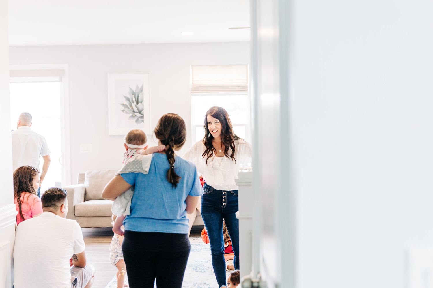 A woman with a welcoming smile, inviting her friends into her home